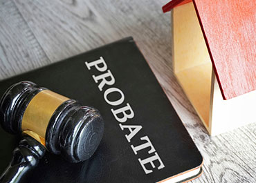Probate law book, gavel, and house model. Choosing a probate attorney.